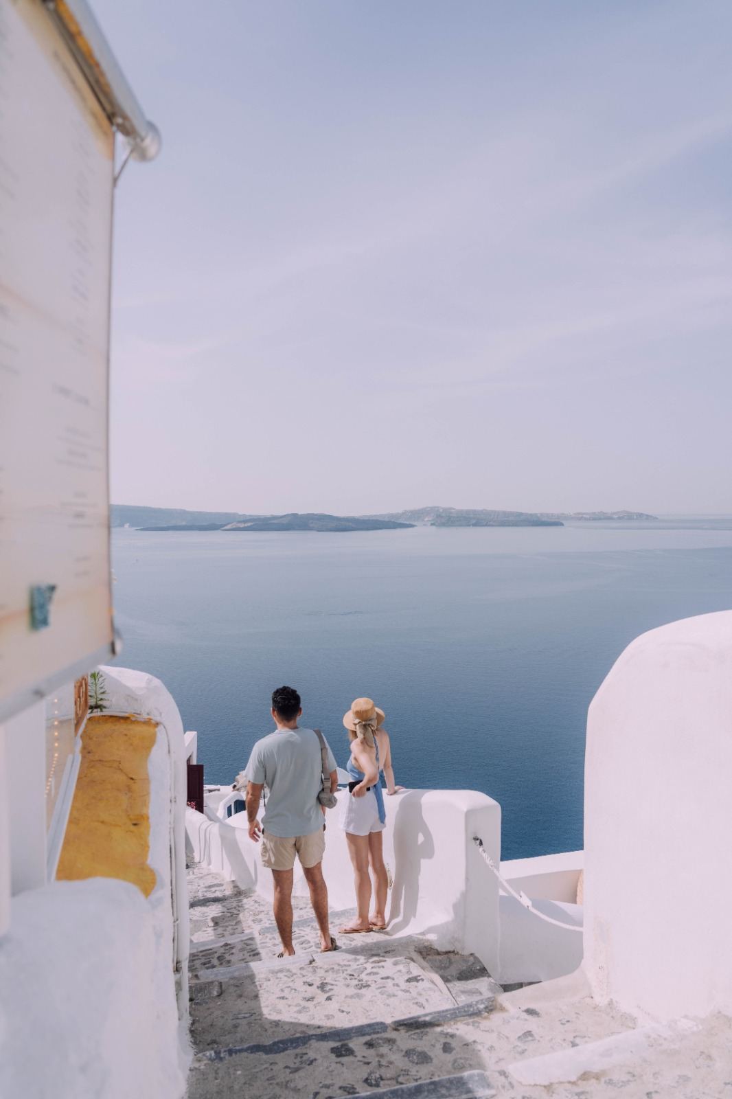Couple walking through whitewashed Greek island architecture above the sea