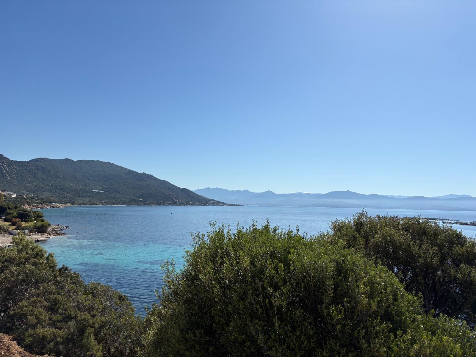 Sheltered bay with clear blue water, green hills and distant mountains